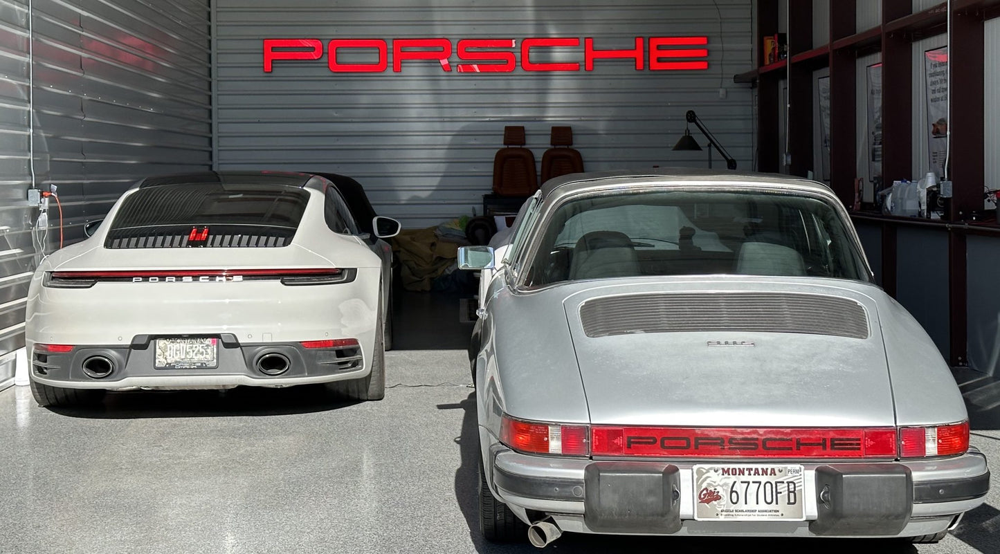 A red LED sign with the Porsche logo illuminated on a wall